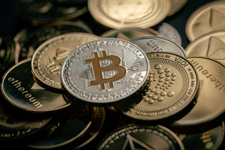 close up shot of a silver Bitcoin in a stack of other digital cryptocurrencies