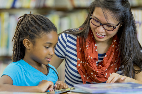 child studying with her tutor in a library