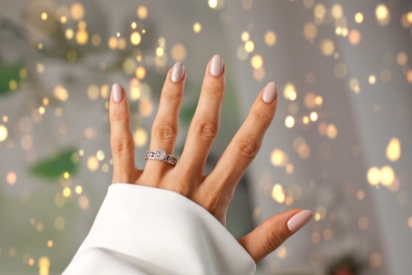 closeup of hand with engagement ring in front of Christmas lights